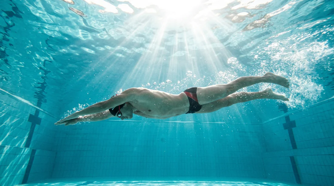 Nageur sous l'eau dans une piscine lumineuse